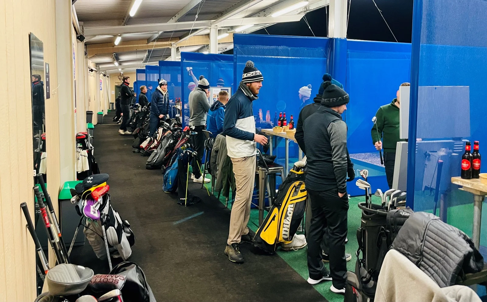 Players competing across the floodlit Toptracer bays during a tournament evening at Winchester Golf Academy